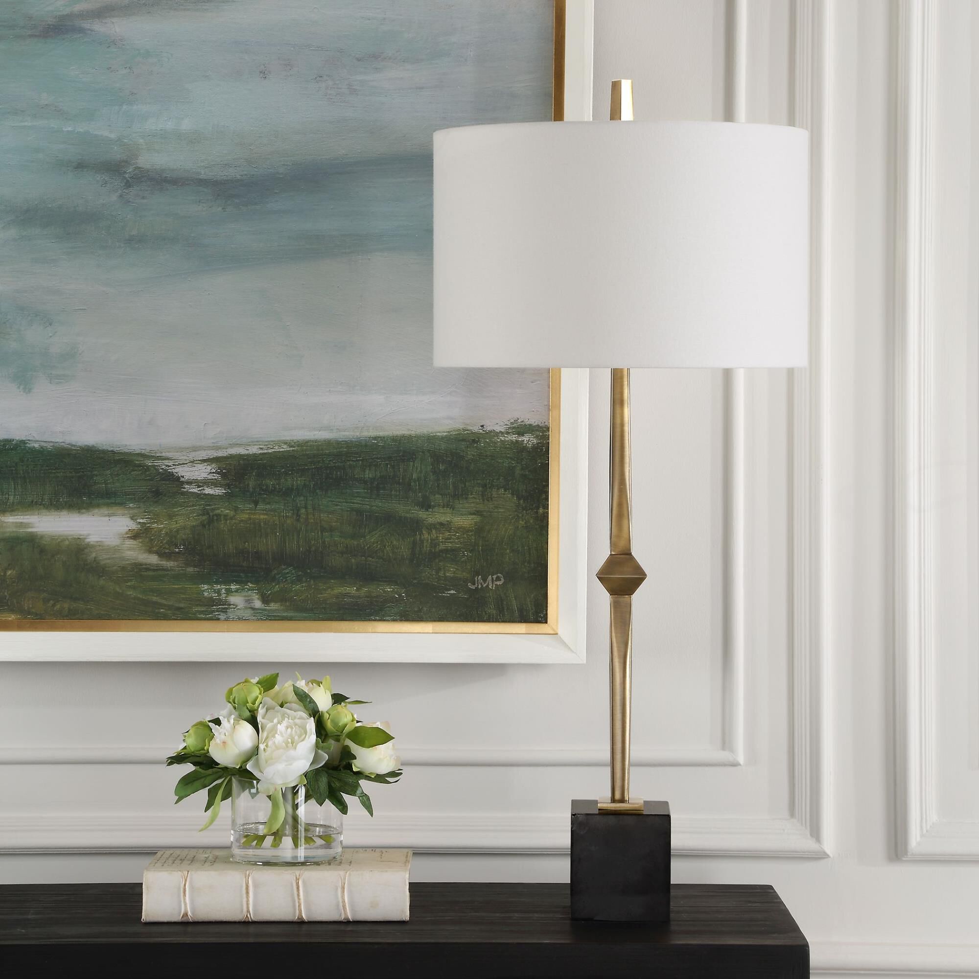 Shown in The Suranne Table Lamp Features A Slender Metal Column In A Sophisticated Plated Antique Brass Finis finish and Round Drum Hardback shade