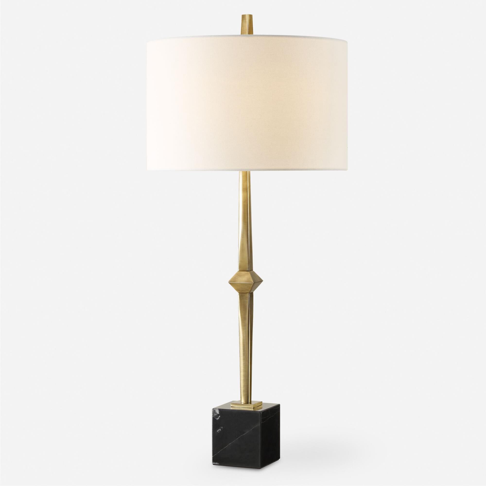 Shown in The Suranne Table Lamp Features A Slender Metal Column In A Sophisticated Plated Antique Brass Finis finish and Round Drum Hardback shade