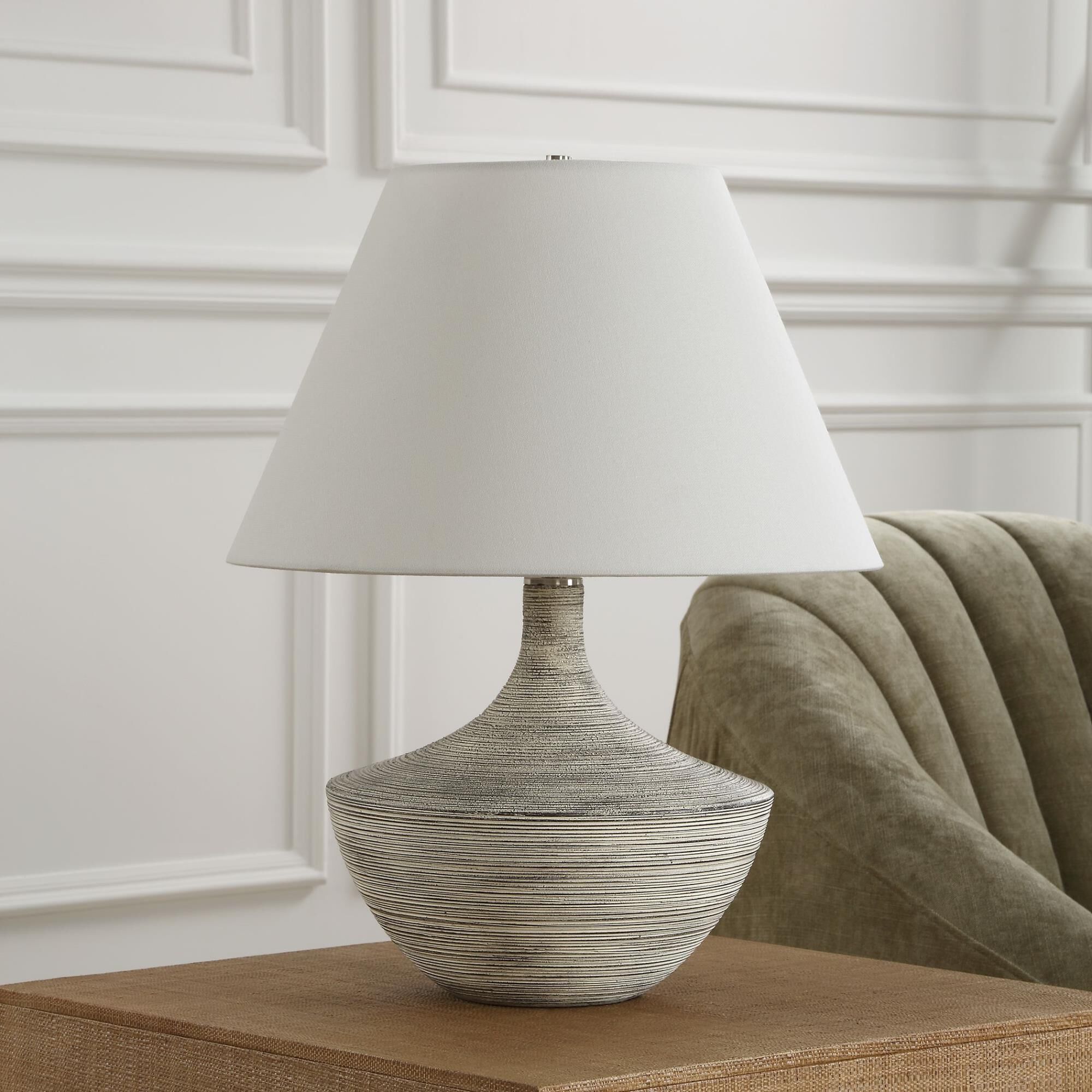 Shown in Where Vintage Charm Meets Contemporary Design, The Carafe Table Lamp Features A Charcoal Ceramic Bas finish and Round Hardback shade