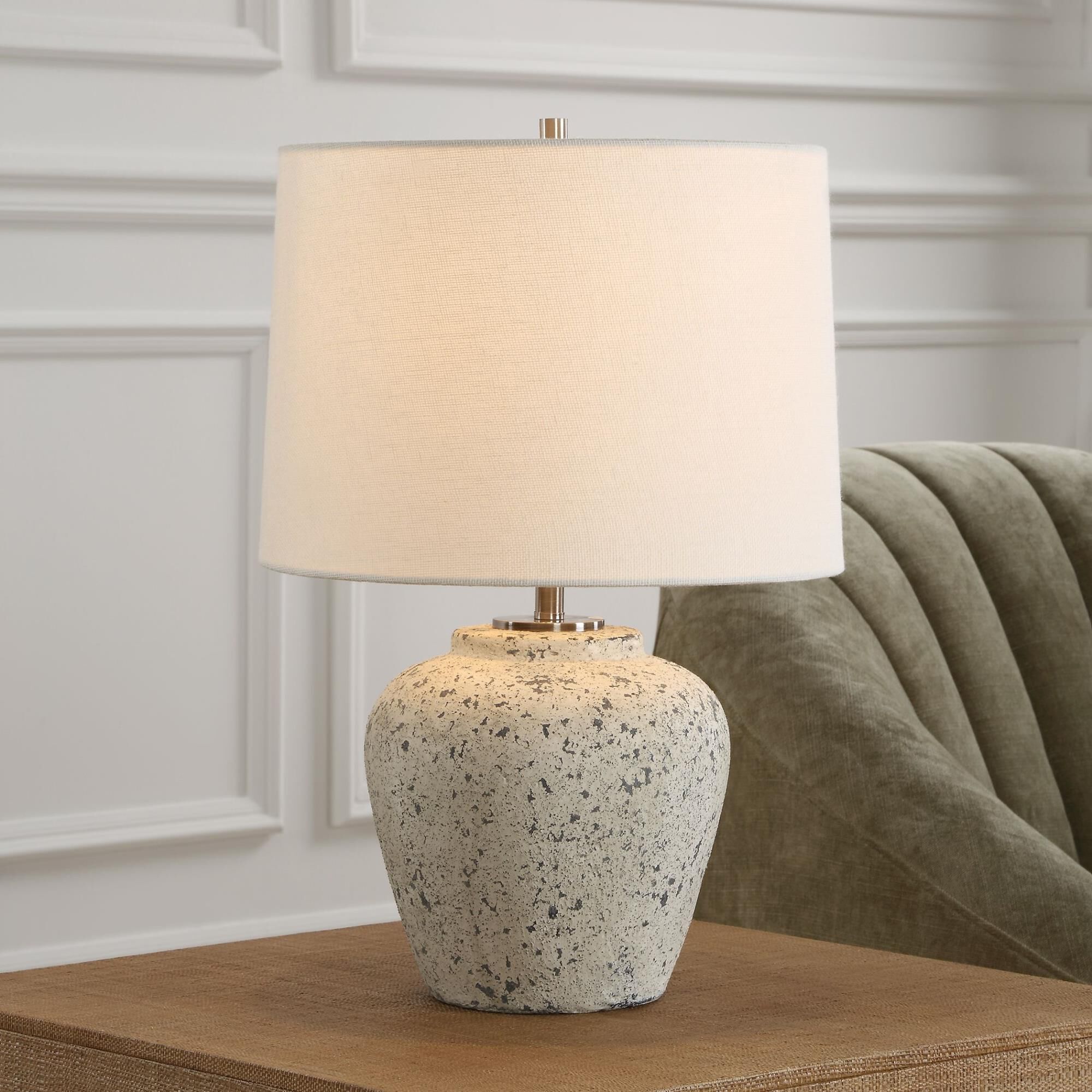 Shown in The Rupture Table Lamp Features A Heavily Distressed Aged Ivory Finish With Stone Gray Undertones An finish and Round Hardback shade