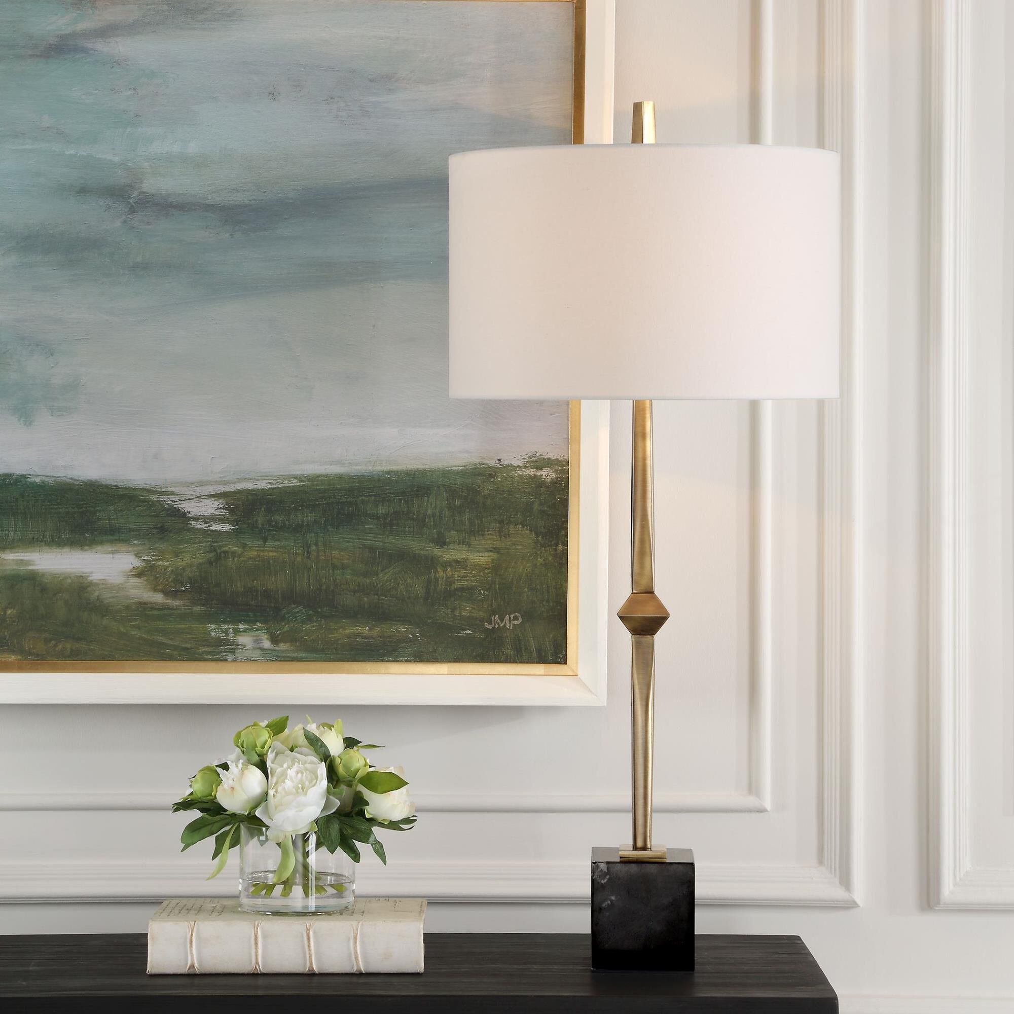 Shown in The Suranne Table Lamp Features A Slender Metal Column In A Sophisticated Plated Antique Brass Finis finish and Round Drum Hardback shade