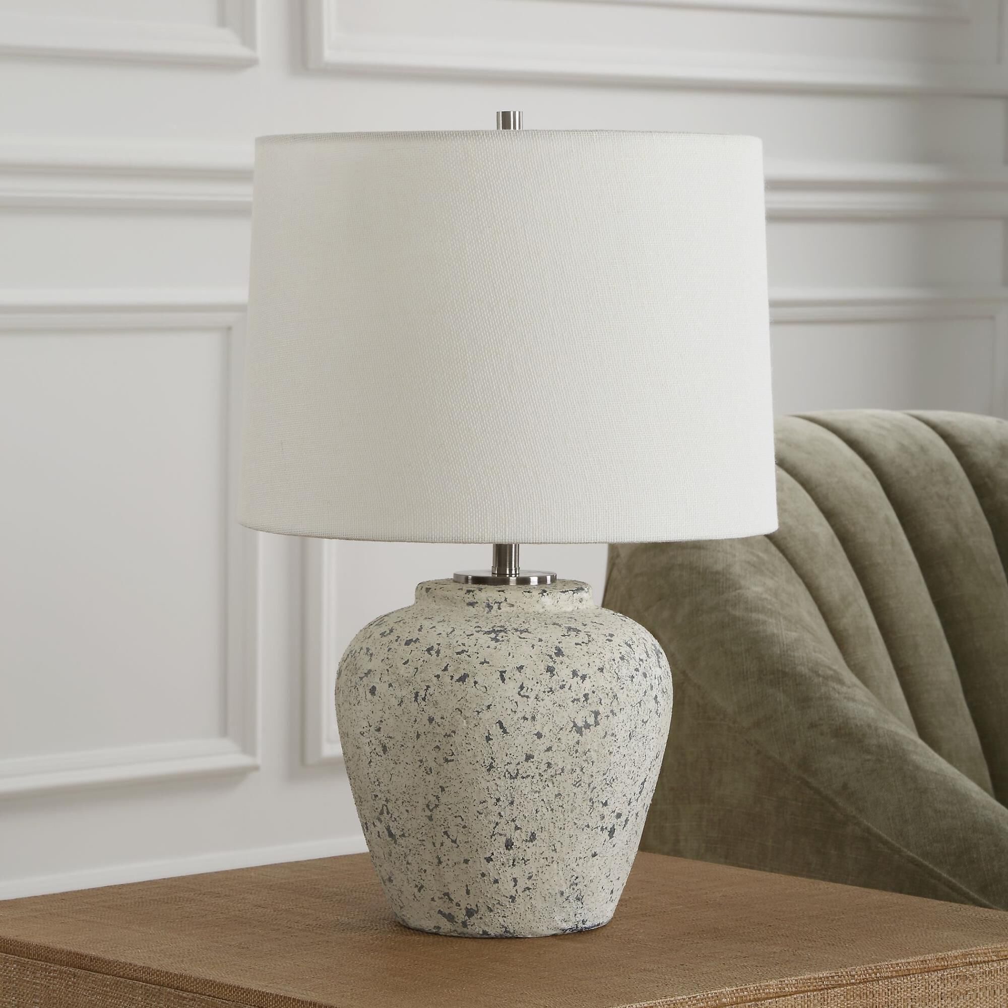 Shown in The Rupture Table Lamp Features A Heavily Distressed Aged Ivory Finish With Stone Gray Undertones An finish and Round Hardback shade