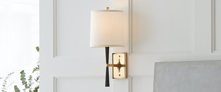 Elegant wall sconce hanging above bed frame from Capitol Lighting